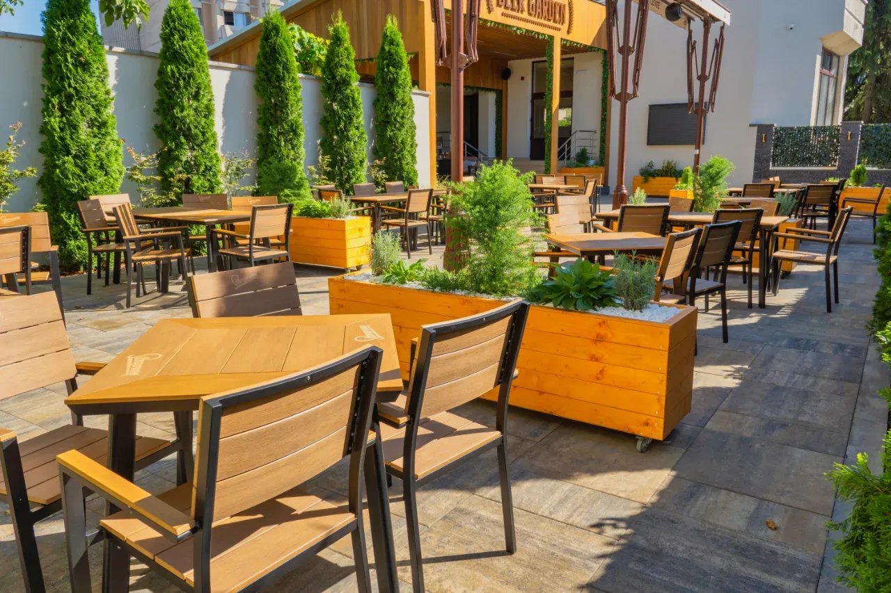 Terasa Beer Garden de la Hotel Cetate, cu mese din lemn, jardiniere și tuia